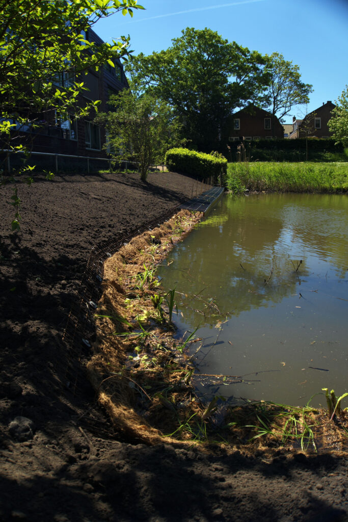 Een foto van een oever met een flauwe bocht erin waar de HIP Groen Natuurvriendelijke Beschoeiing is aangebracht.